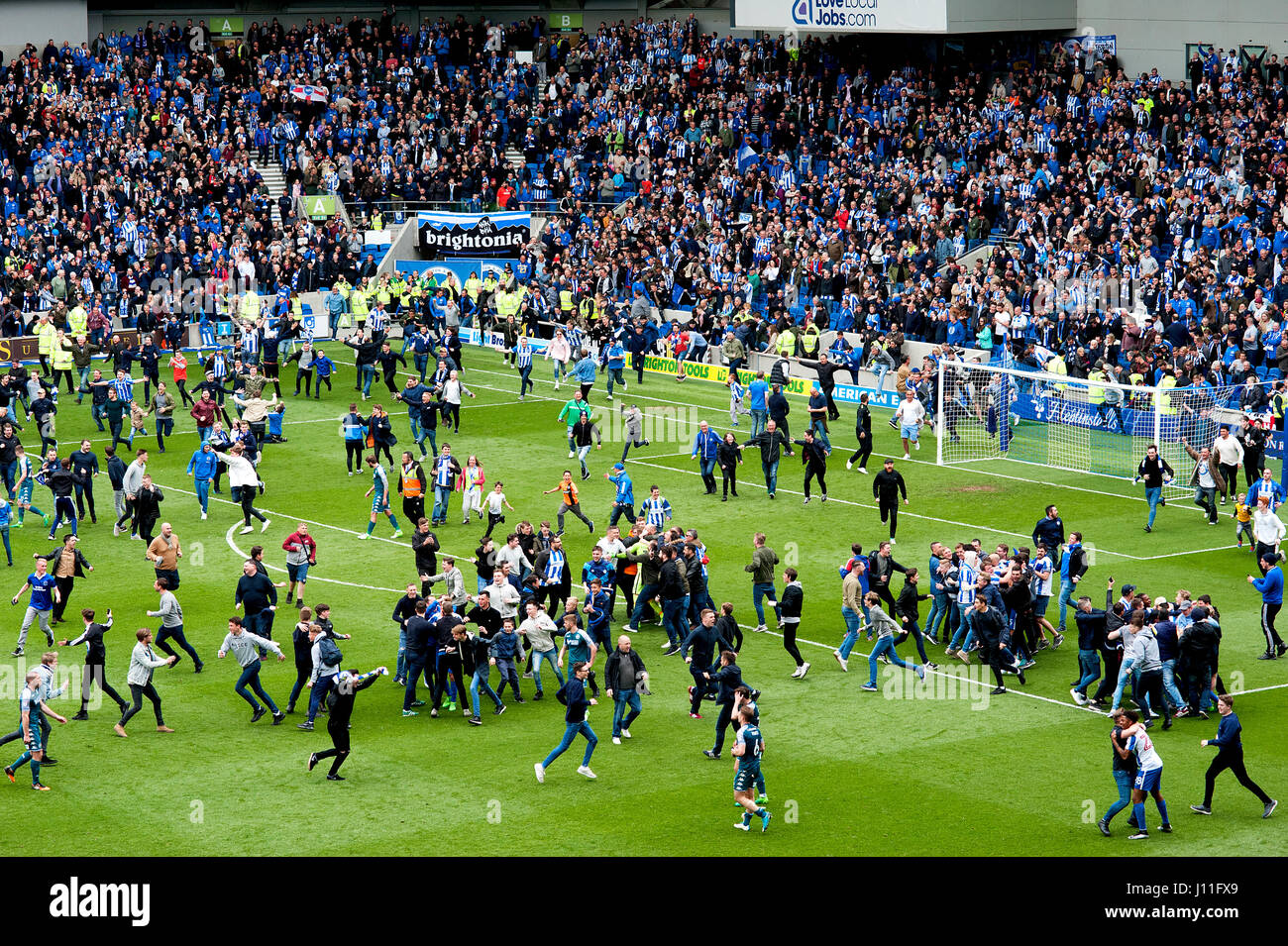 Los fans de la Brighton y Hove Albion football club invaden el tono para celebrar el ascenso a la Premier League en el estadio de Amex, el 17 de abril de 2017. Foto de stock