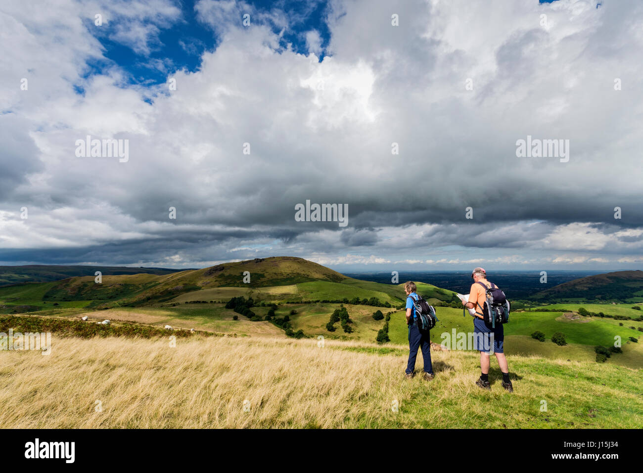 Los paseantes sobre Willstone Hill, con Caer Caradoc en la distancia, con la esperanza de Bowdler Hills, cerca de Church Stretton, Shropshire, Inglaterra, Reino Unido. Foto de stock