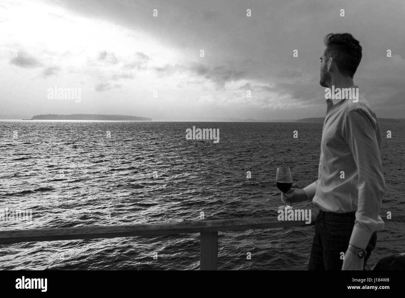 Hombre contemplativo con vino tinto en el mar Foto de stock