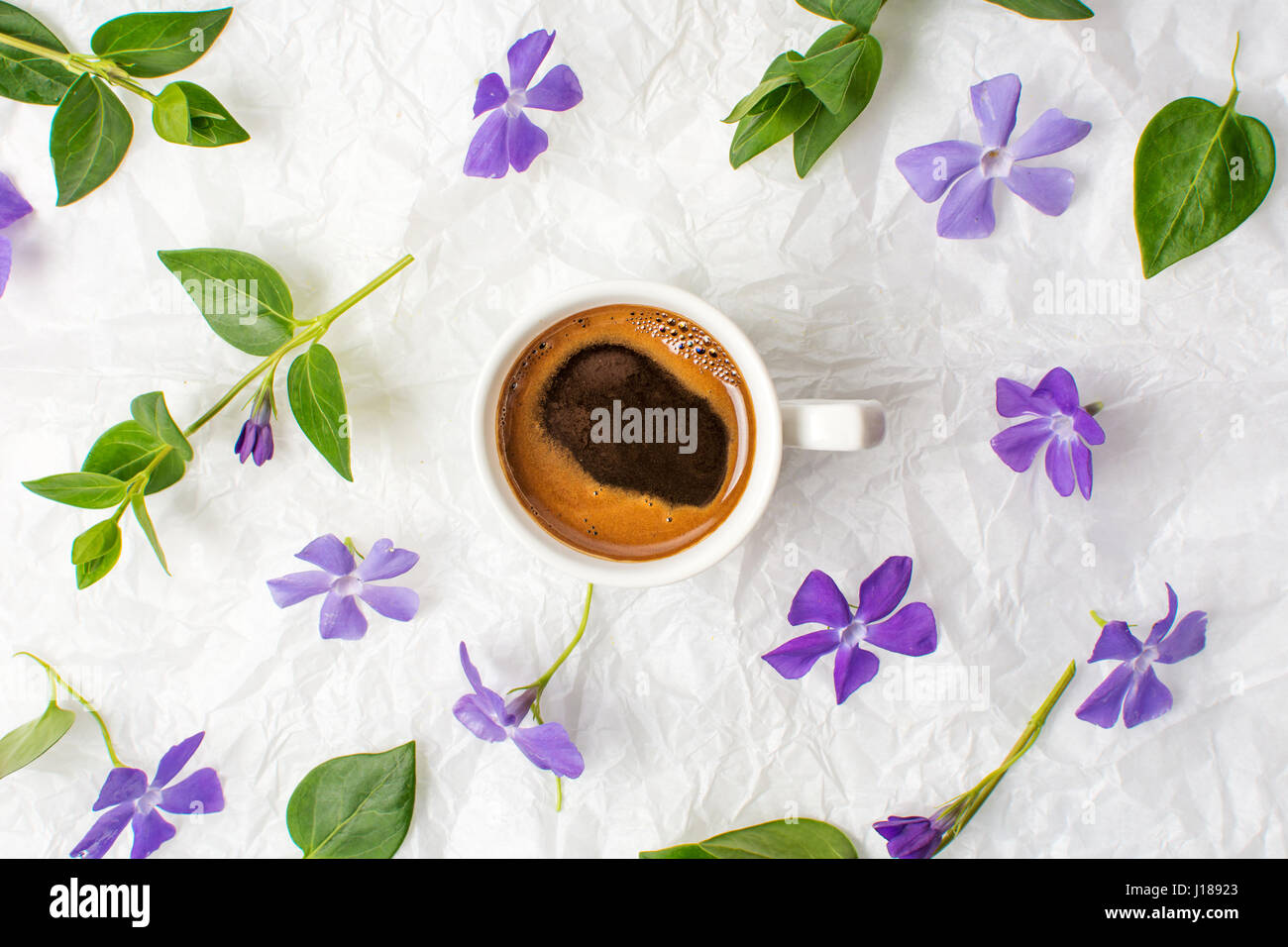 Taza de café y flores de primavera en púrpura sábanas Foto de stock