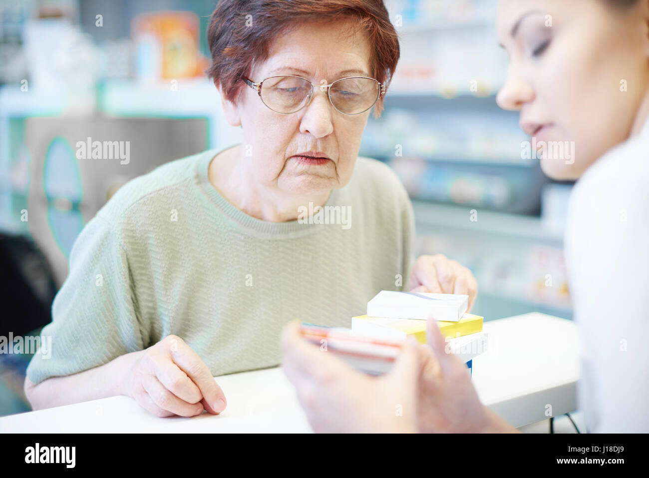 Mujer mayor con el farmacéutico en el mostrador de recepción Foto de stock