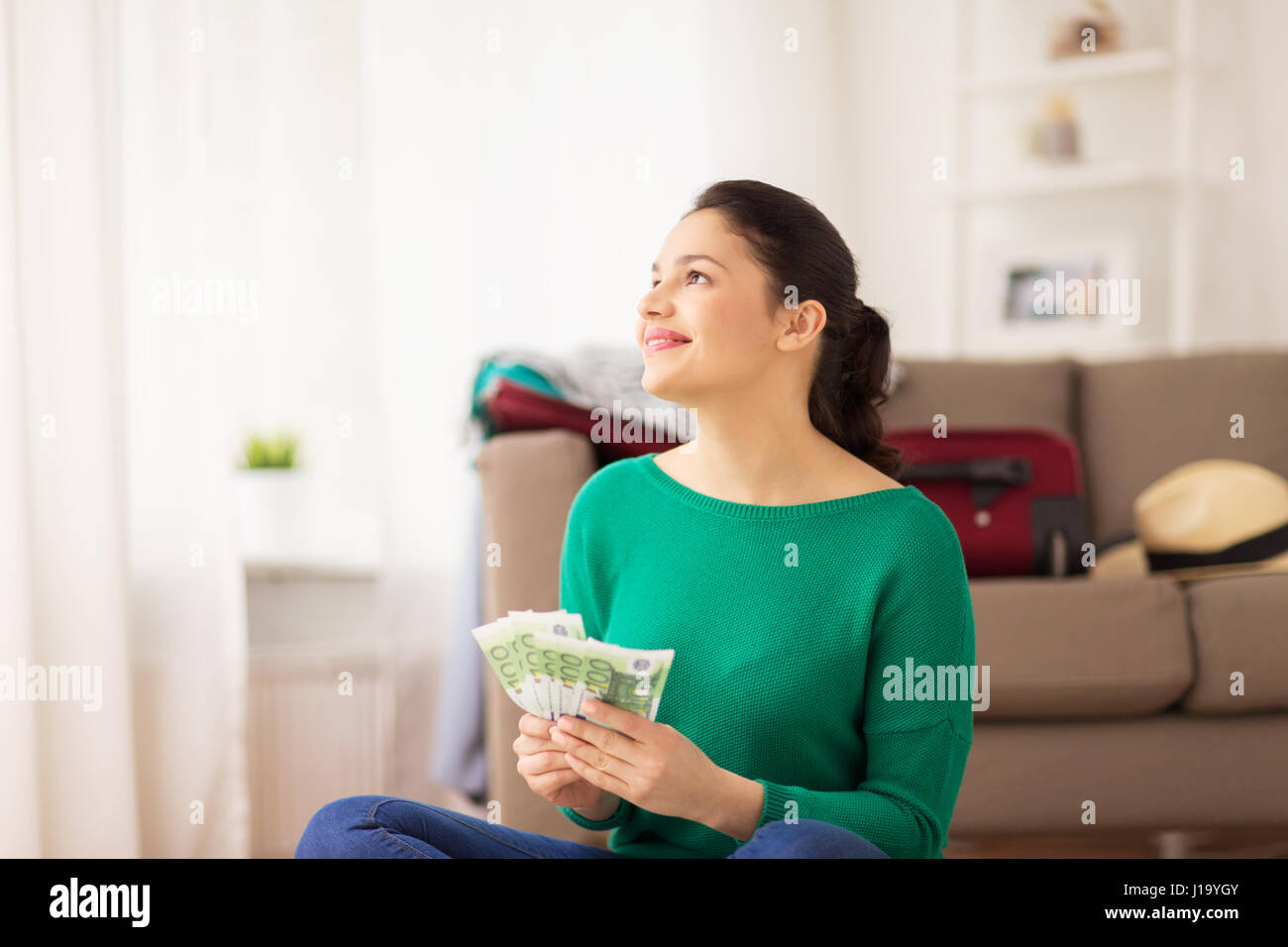 Mujer feliz con dinero y bolsa de viaje en casa Foto de stock