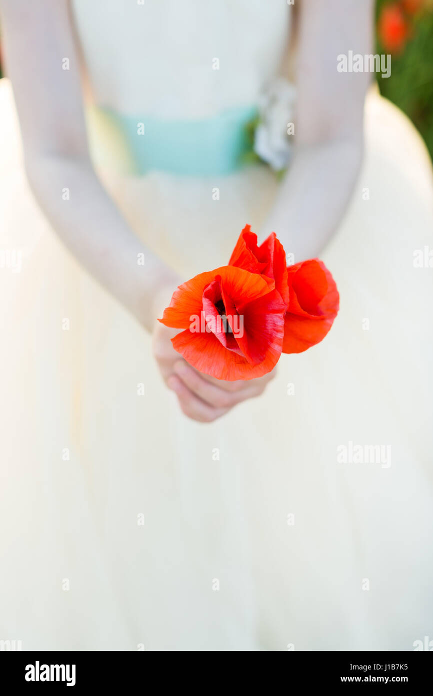 Amapolas, agricultura, producción y Ecología, naturaleza y concepto de  verano - Cierre de amapola roja las yemas en dos manos de una niña vestida  de blanco vestidos de boda en un campo