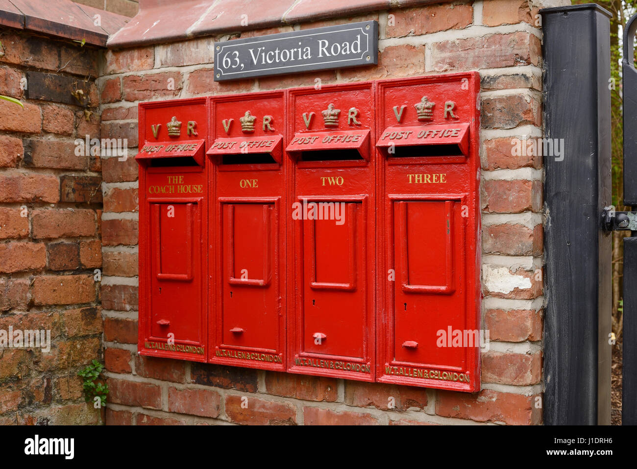 Una fila de cuatro casillas de correo de reproducción vintage fuera un multi propiedad de ocupación. Foto de stock