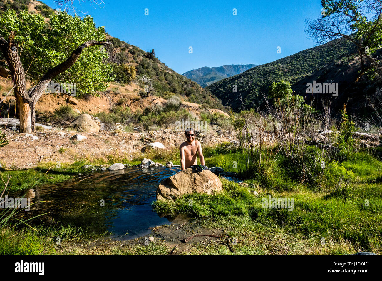 Un hombre joven bañarse en una piscina natural de agua caliente en el