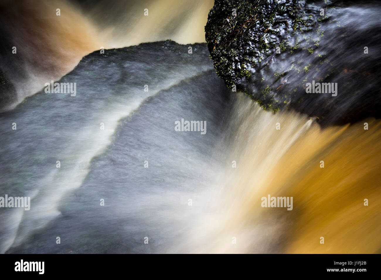 Cerca del agua que fluye sobre las rocas en un tiempo de exposición. Foto de stock