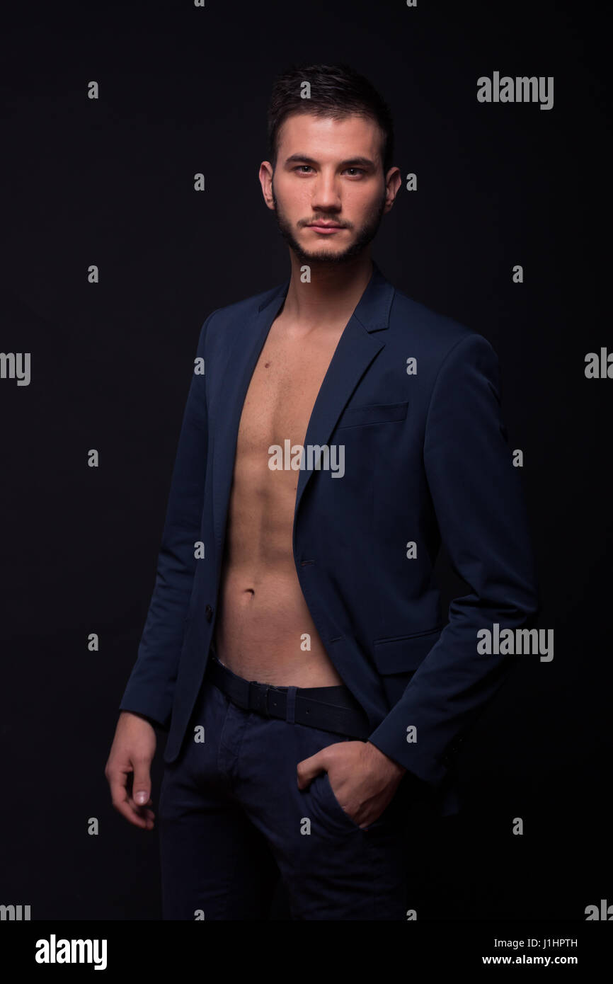 Un hombre adulto joven, 20s modelo, mirando a la cámara, descamisados,  montar abs pecho, traje de chaqueta azul, pantalón negro, fondo studio  Fotografía de stock - Alamy
