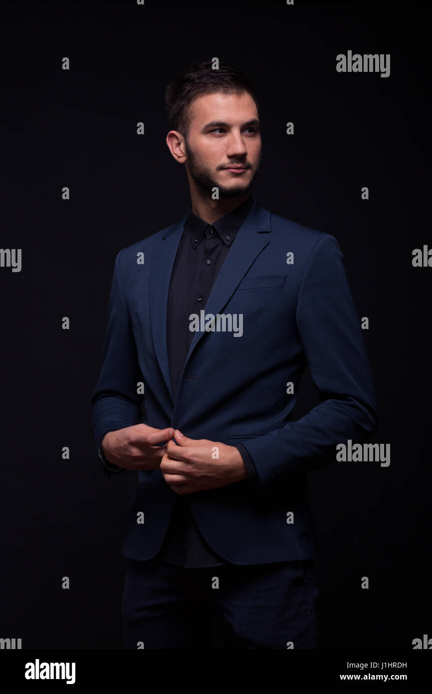 Un hombre adulto joven, mirando hacia los lados, fondo negro, camisa negra,  abotonarse traje chaqueta Fotografía de stock - Alamy