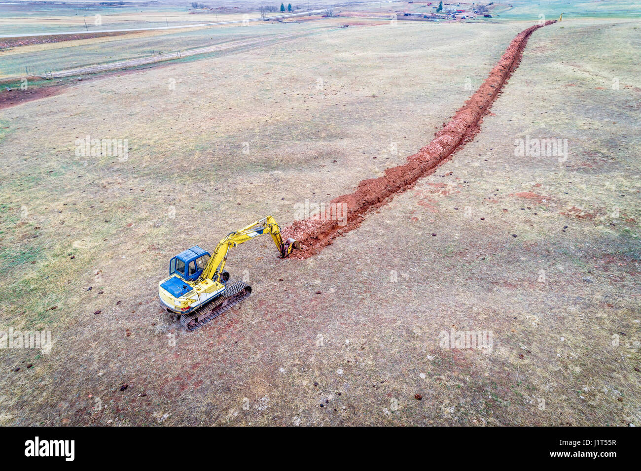Excavadora retroexcavadora cavando una zanja de riego en estribaciones