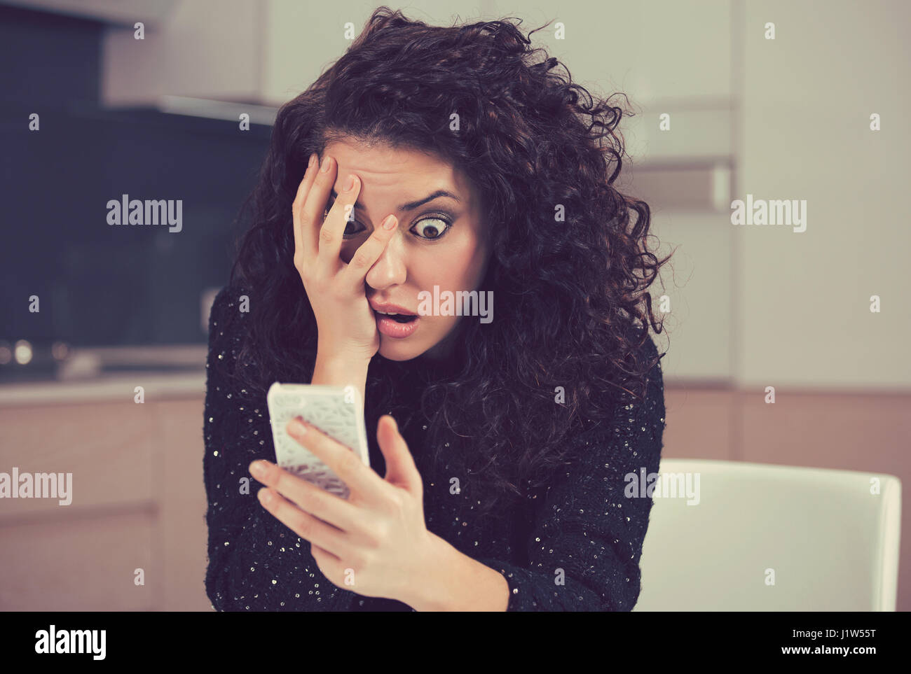 Conmocionó a jóvenes ansiosos una mujer mirando teléfono viendo malas noticias fotos mensaje con miedo la emoción en la cara Foto de stock