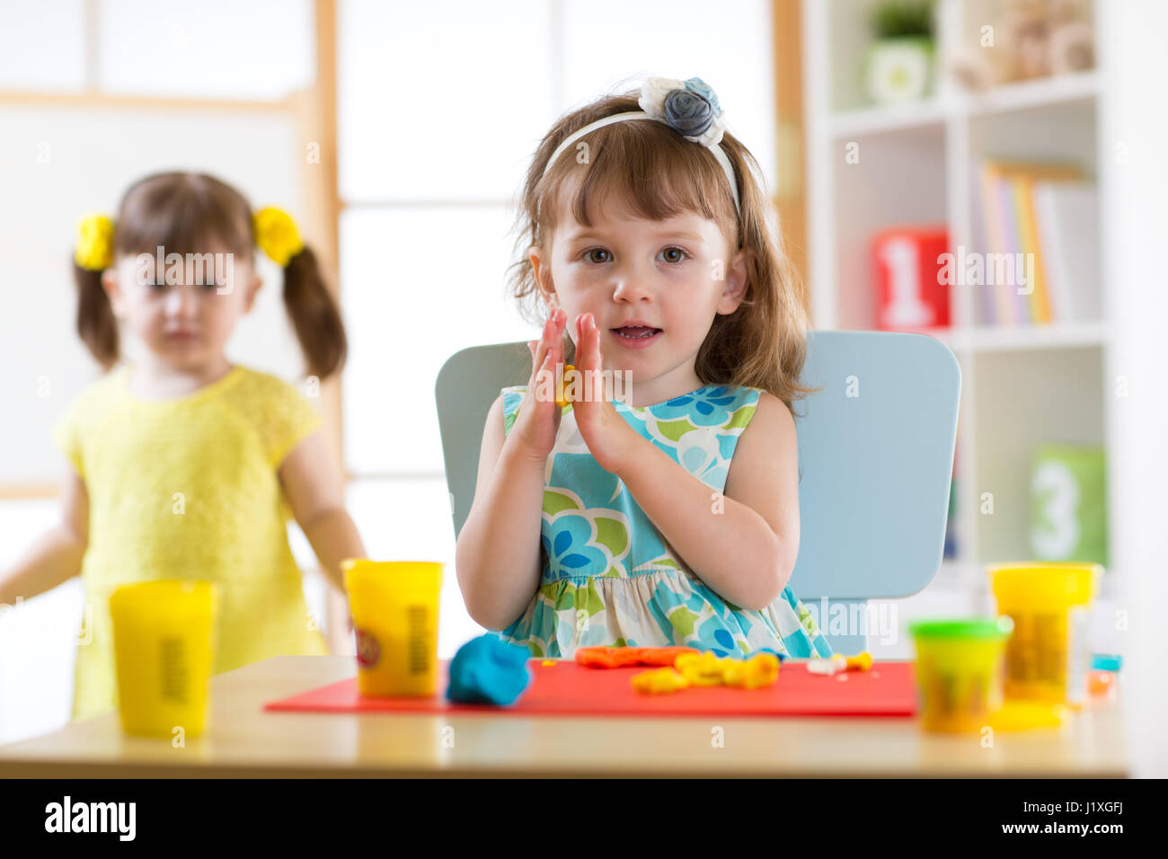 Cute Little Girl moldes de plastilina en la mesa Foto de stock