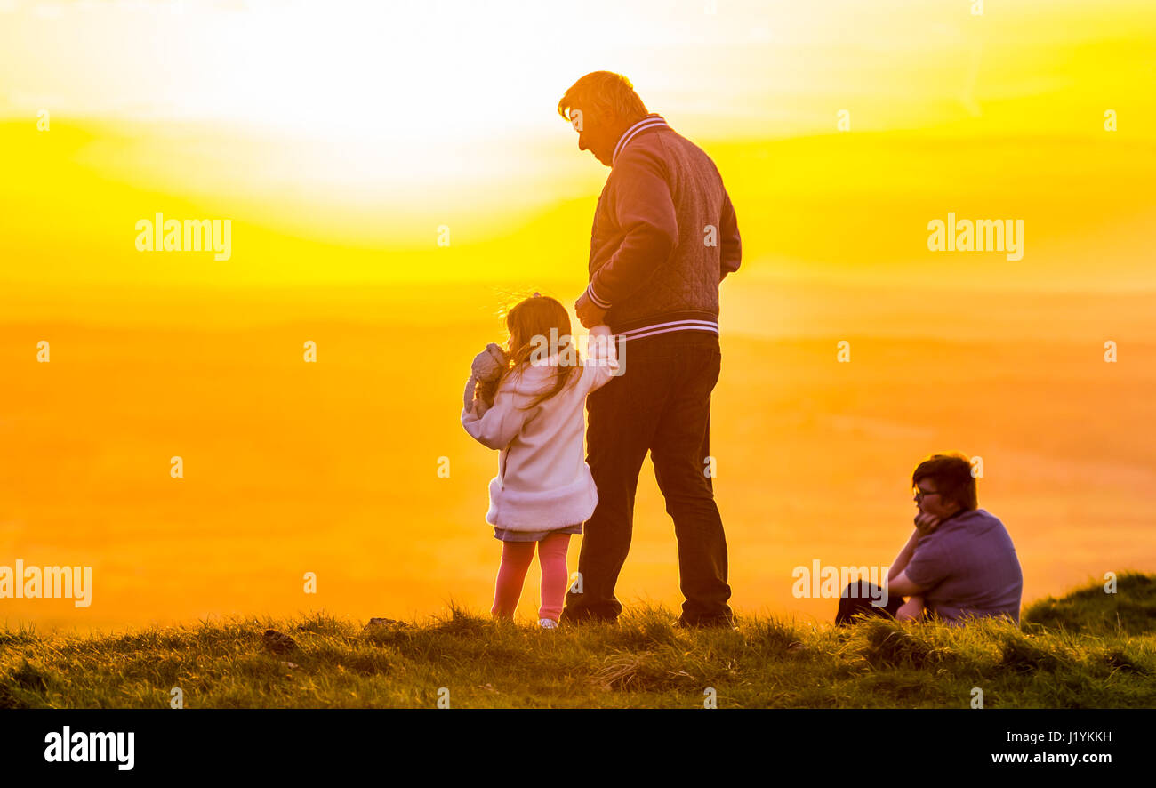 El afecto entre los miembros de la familia de pie sobre una colina mirando el cielo nocturno. Foto de stock