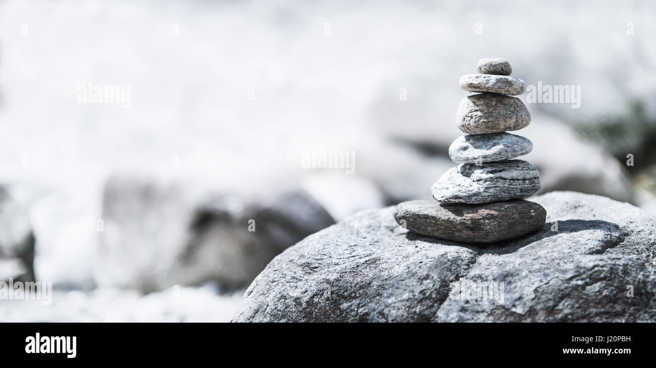 Zen grises piedras apiladas junto a un río Foto de stock