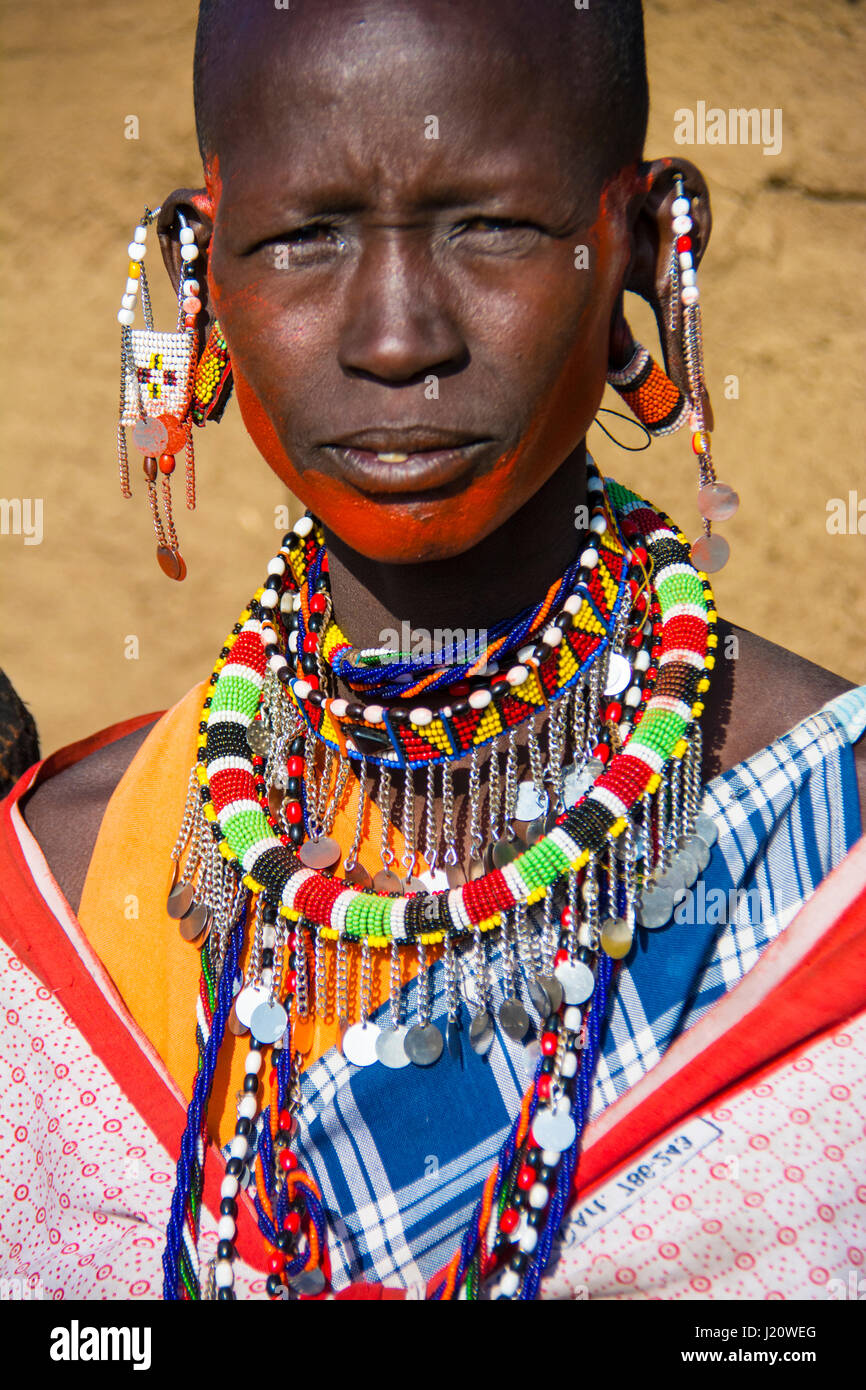 Retrato de una Mujer masai vistiendo ropas tradicionales y joyas en una aldea cerca de los Masai Mara, Kenia, África Oriental Foto de stock