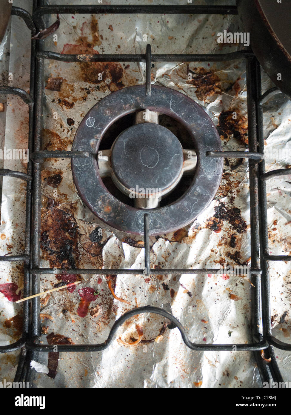 Las sucias y asquerosas y oxidada Top de cocina de gas vitrocerámica con  bits de debajo de la lámina metálica con trozos de alimentos y el Alto  Detaul brilla con grietas y