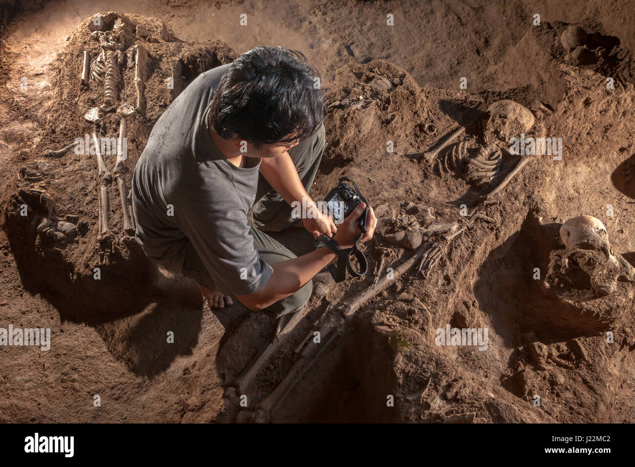 Un arqueólogo indonesio que toma fotos de los esqueletos homínidos prehistóricos en el sitio de excavación de Gua Harimau, Sumatra, Indonesia. Foto de stock