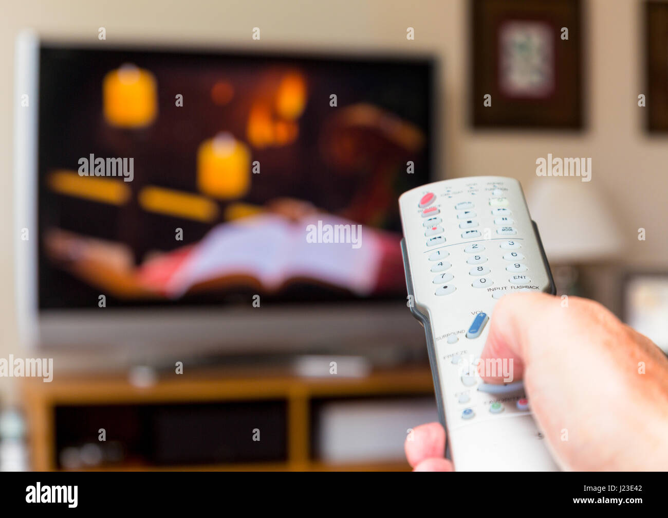 La persona que está mirando la televisión y navegar por los canales con el mando a distancia del televisor Foto de stock
