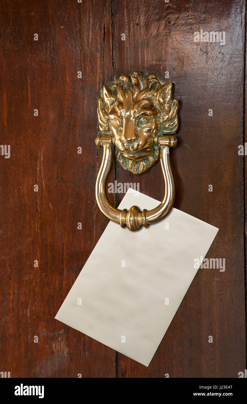 Sobre en blanco con espacio para texto colocado debajo de una cabeza de león de bronce de puerta en puerta de roble antiguo martinete Foto de stock