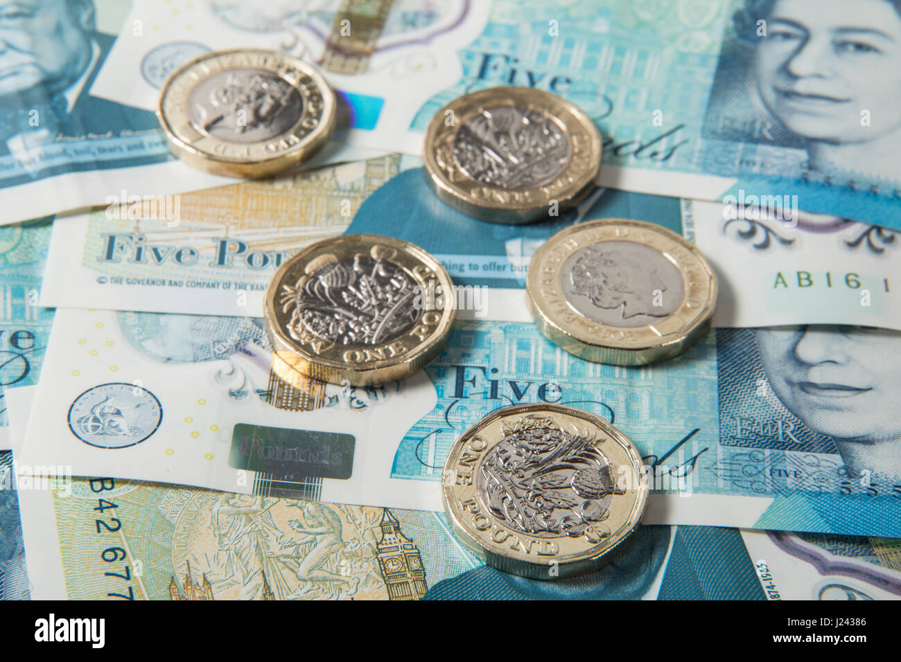 Las nuevas monedas de 1 libras británicas sobre un fondo de UK £5 libras notas Foto de stock