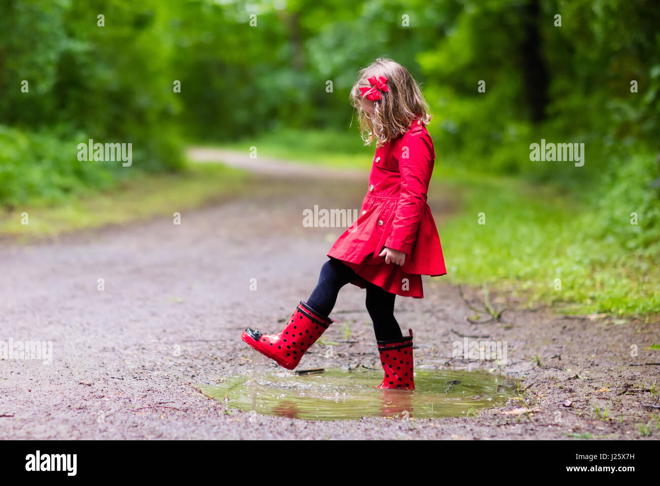 Niña jugando en verano lluvioso park. Niño con mariquita rojo paraguas,  impermeable y botas de saltar en charcos de barro y bajo la lluvia. Kid  walkin Fotografía de stock - Alamy