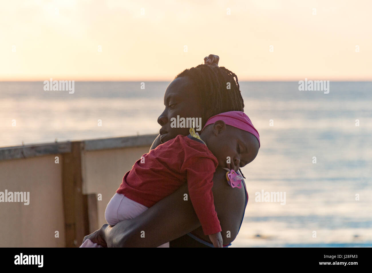 Jamaica, Negril, la hora de acostarse, la madre lleva a su bebé turbulette Foto de stock