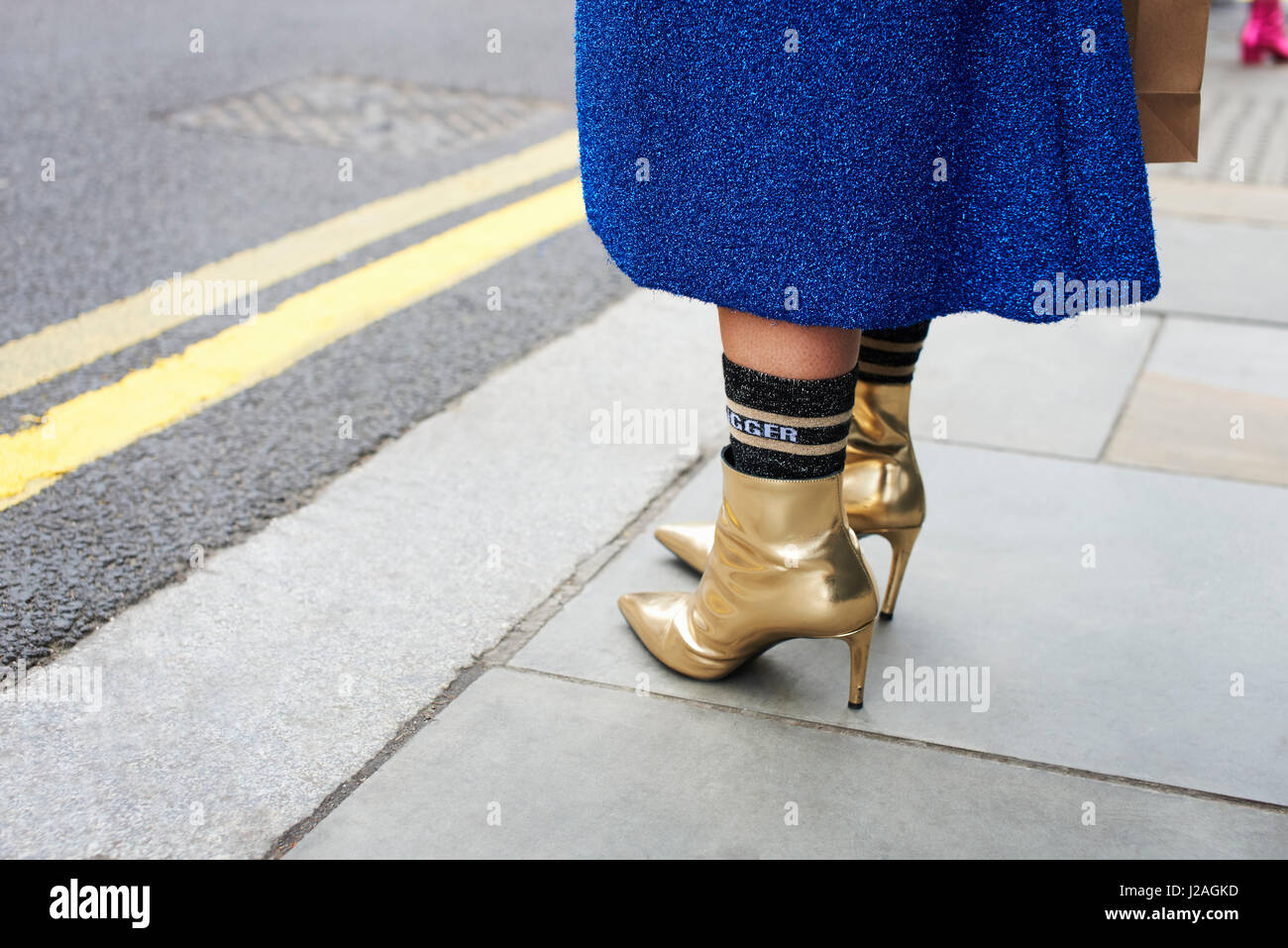 Londres - Febrero, 2017: Bajo la sección de mujer vestidos de lana azul falda, calcetines y botines de oro que estaban en la calle durante la Semana de la Moda de Londres, horizontal Foto de stock