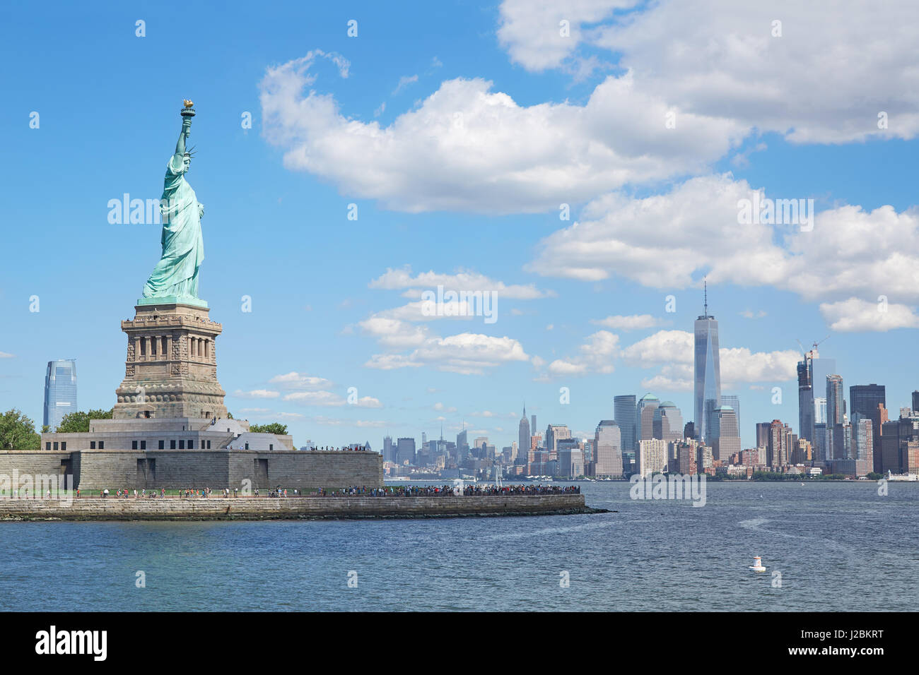 La estatua de la libertad y de la ciudad de Nueva York en un día soleado, cielo azul y acercando las nubes blancas Foto de stock