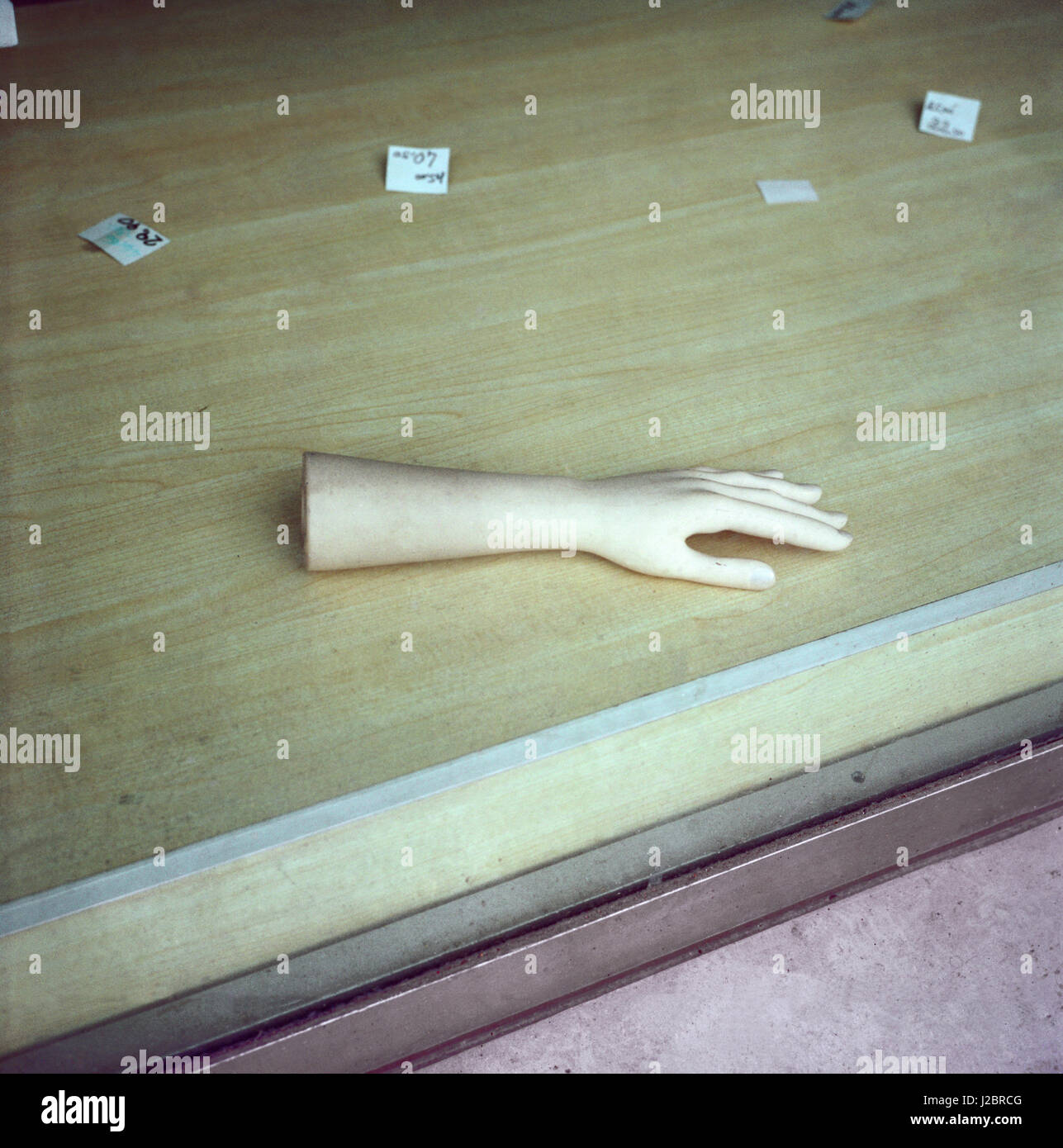 La muñeca de la mano izquierda ficticia sobre el piso en una ventana y etiquetas de precio de fabricación alrededor Foto de stock