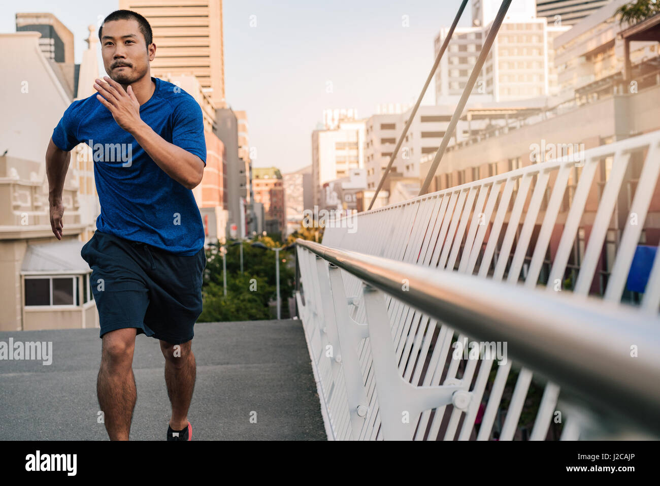 Joven Asiático Atlético hombre corriendo a través de la ciudad. Foto de stock