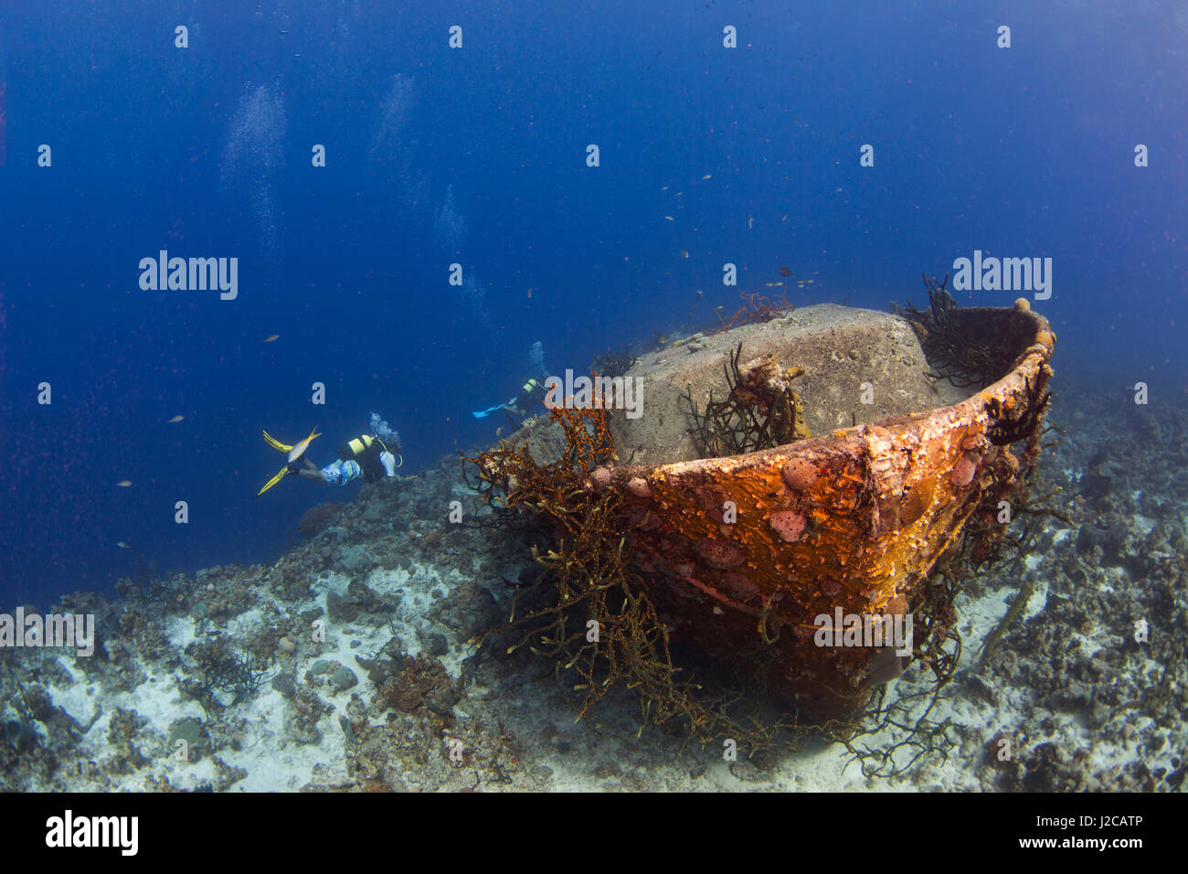 Dos buzos nadan por encima de un naufragio que descansa a lo largo de la cornisa de un arrecife de coral durante una inmersión en la Bahía de Cochinos, cerca de la ciudad de Playa Girón, Cuba Foto de stock