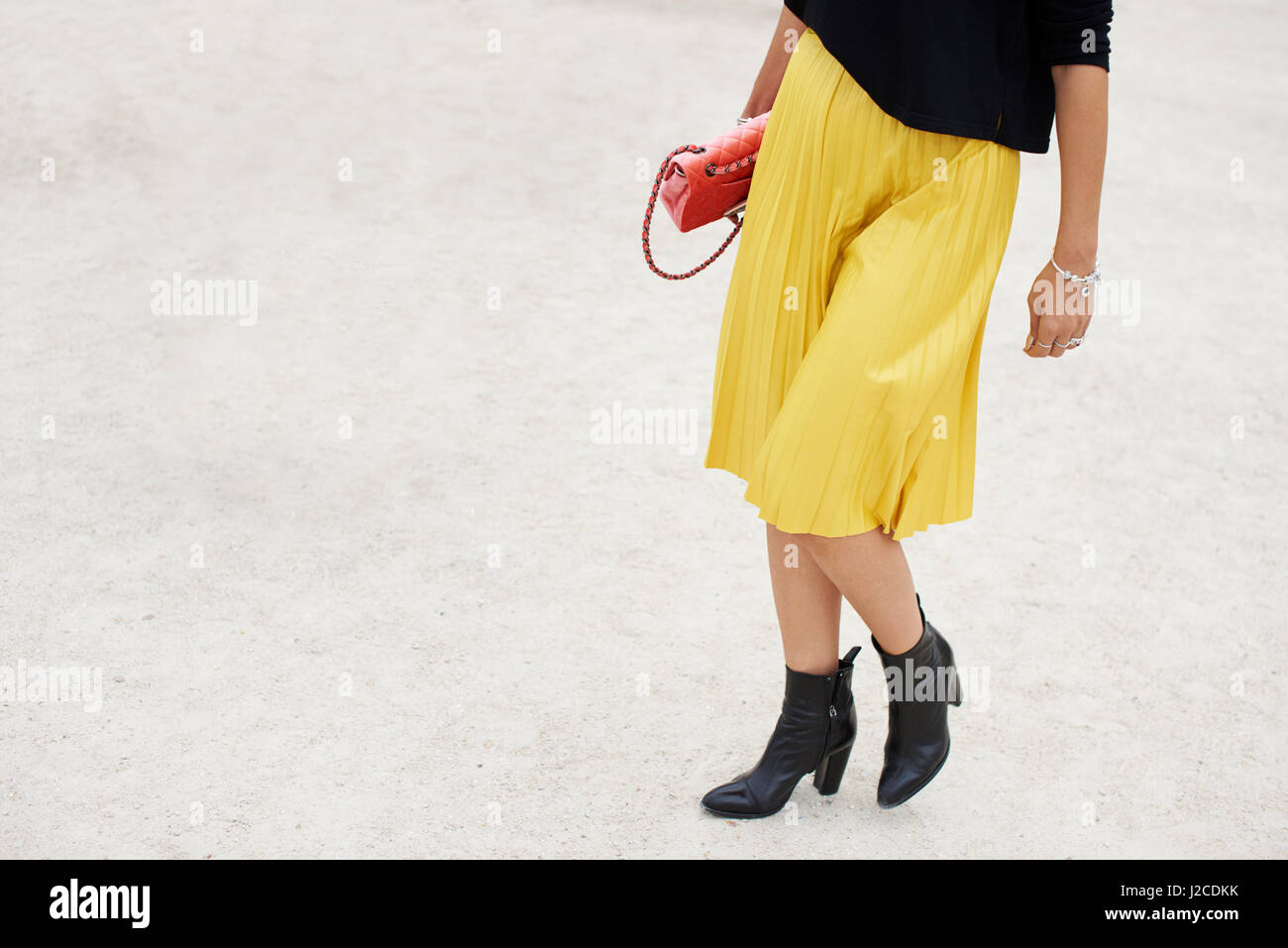 Bajo la sección de la mujer en la falda plisada amarilla caminando en el  parque Fotografía de stock - Alamy