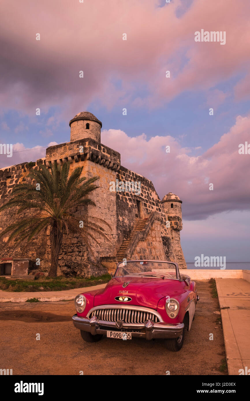 Cuba, Cojimar. Clásico americano coche aparcado delante de una fortaleza. Foto de stock