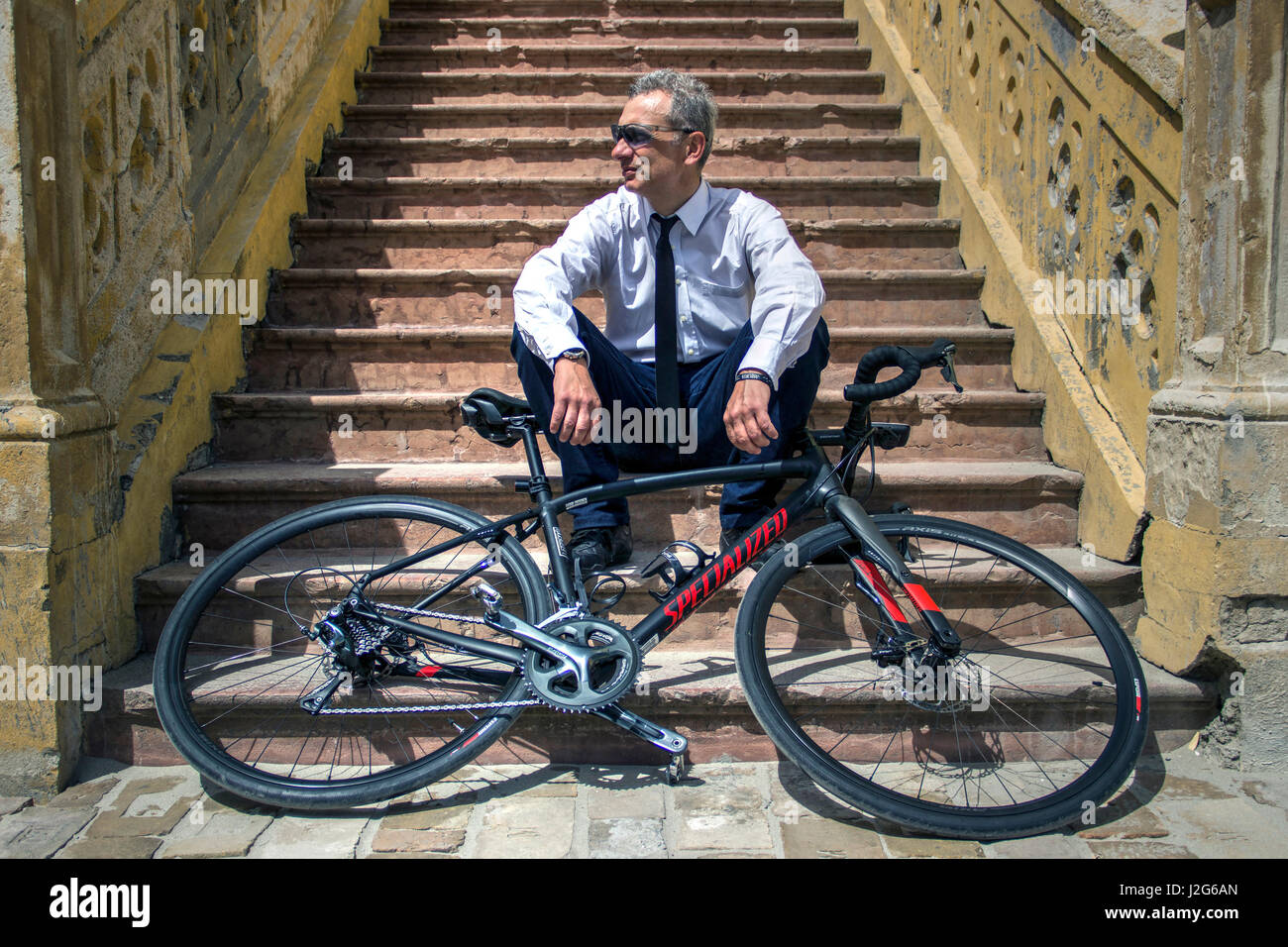 Belgrado, Serbia - Ciclista posando en una escalera detrás de su bicicleta. Foto de stock