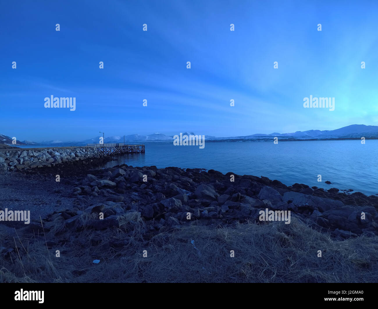 Largo muelle entrar en mar azul al amanecer Foto de stock