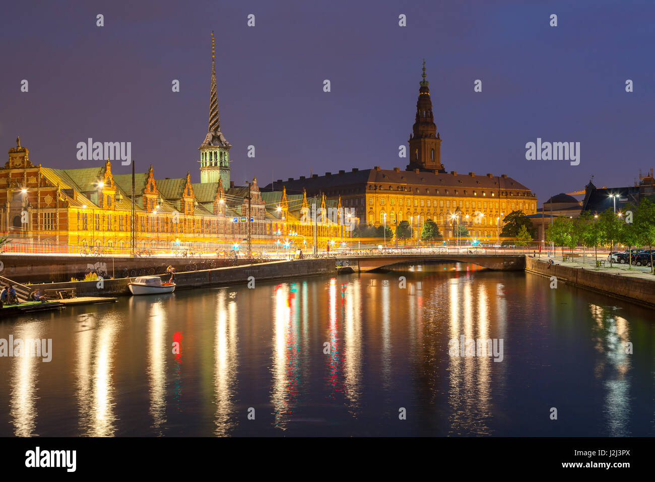 Vista nocturna de Christiansborg Palace y el edificio de la Bolsa a través del canal en Copenhague. Foto de stock