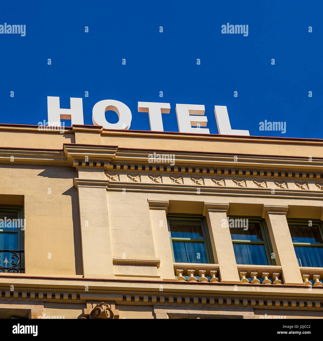 Un moderno hotel firmar en edificio con arquitectura clásica bajo un cielo azul profundo. Foto de stock