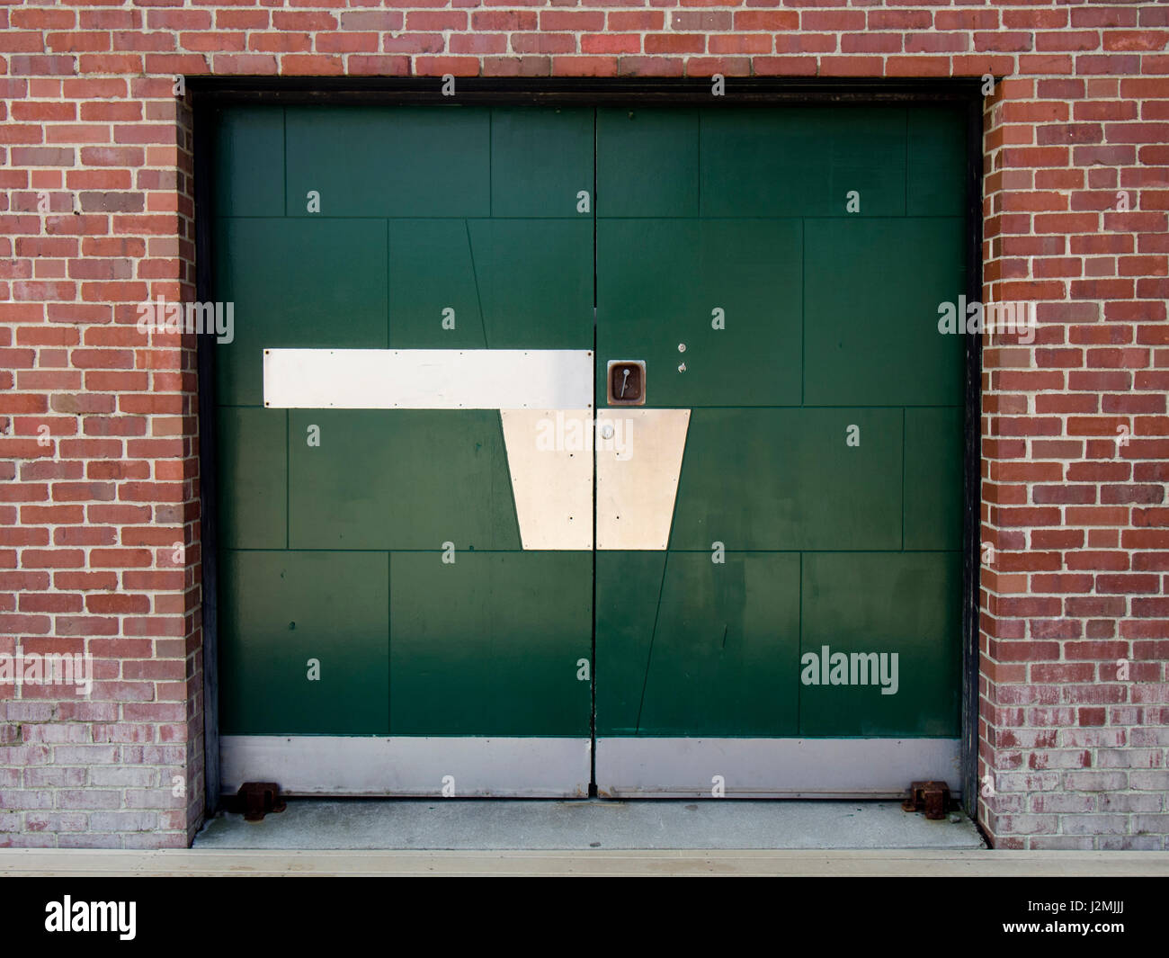 Una puerta de metal pintado de verde en un viejo edificio de ladrillo. Foto de stock
