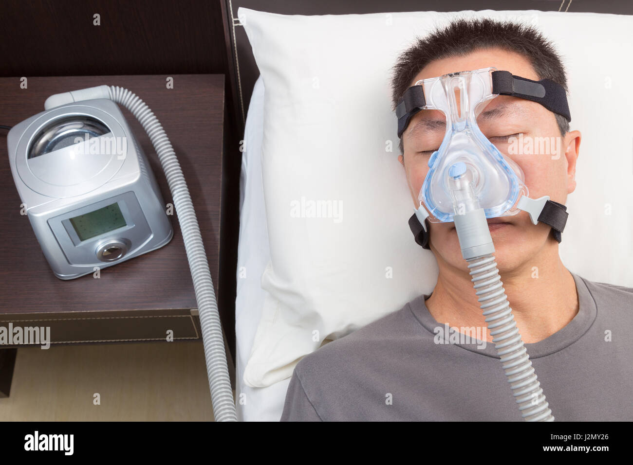 Hombre asiático con apnea del sueño mediante máquina de CPAP, vistiendo  gorras de máscara para conectar el tubo de aire, el enfoque selectivo sobre  el hombre y la sombrerería máscara Fotografía de