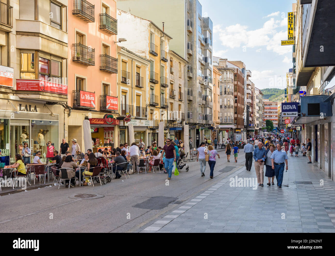 La gente disfruta de su paseo nocturno y sentados en cafés a lo largo de la  principal calle comercial de Cuenca, Calle Carreteria en la nueva ciudad,  Cuenca, España Fotografía de stock -