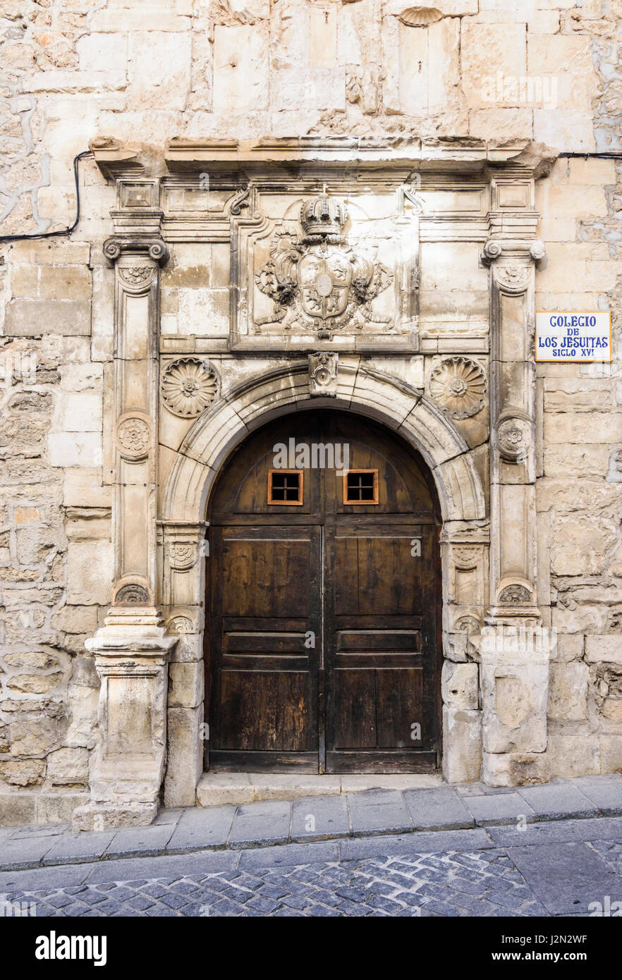 Las puertas dobles de madera y el escudo de armas de los Jesuitas en el antiguo Colegio de los Jesuitas, un edificio histórico en el casco antiguo de la ciudad medieval de Cuenca, España Foto de stock