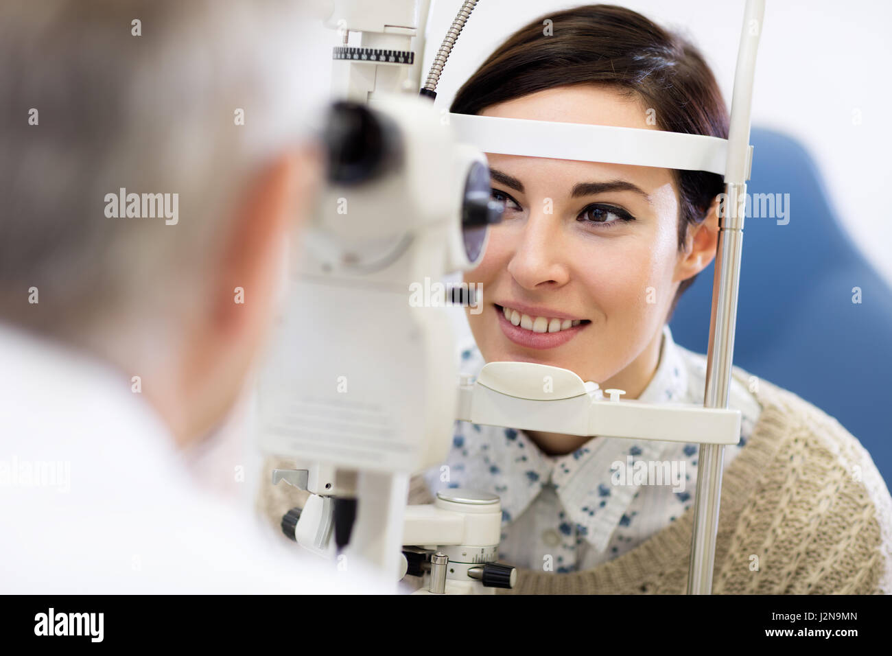Escuchar oscuro mujer mira en el oftalmoscopio para determinar en la clínica de dioptrías Foto de stock