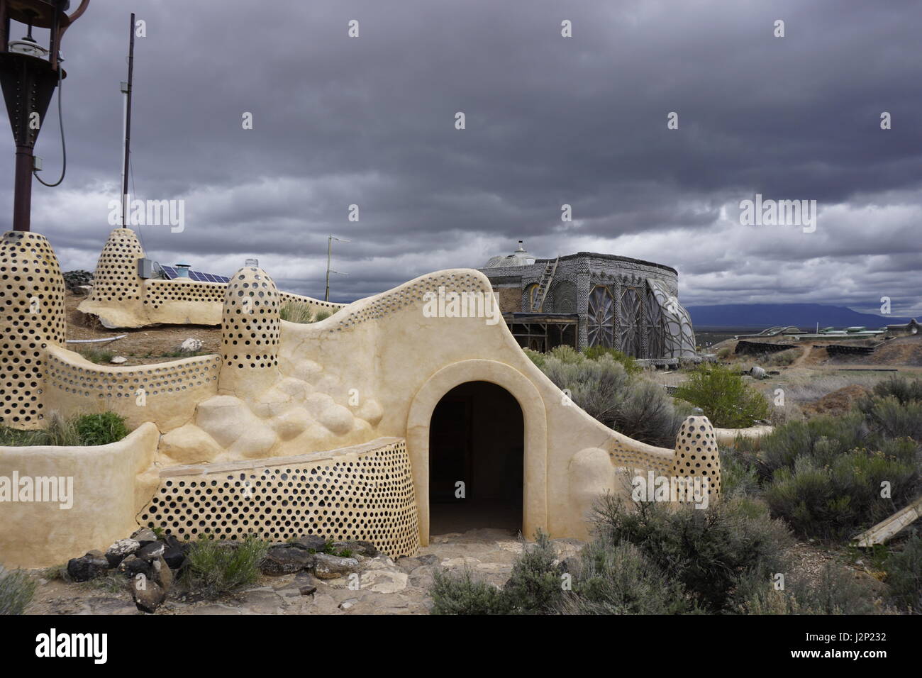Nubes de tormenta rodar dos últimos off-grid, sostenible earthship Biotecture Earthship estructuras en el centro para visitantes cerca de Taos, Nuevo México, EE.UU.. Foto de stock