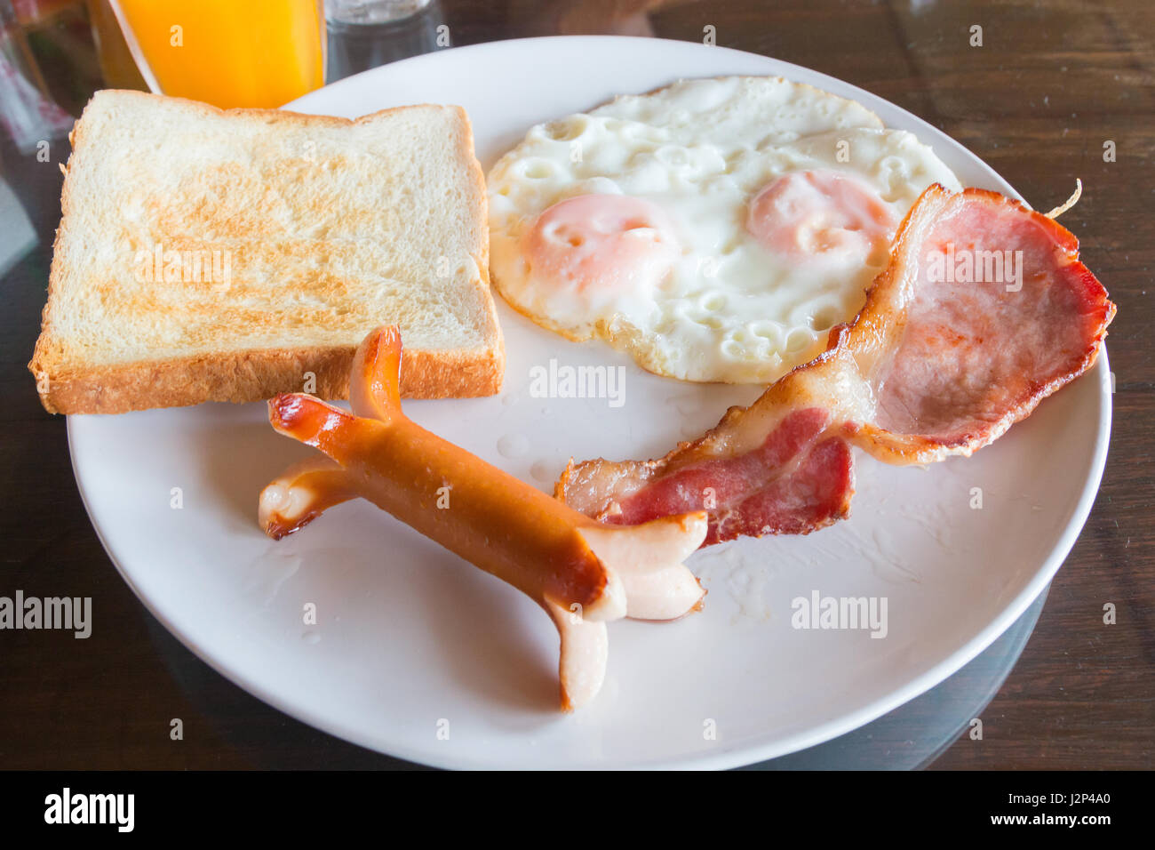 Desayuno insalubres cuestionables con salchicha grasienta, tocino, huevos, doble y tostadas de pan blanco Foto de stock