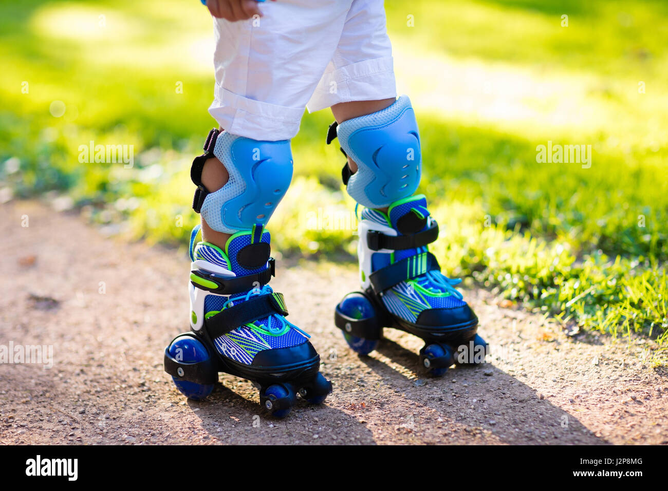 Little Boy aprendiendo a rodillo en verano skate park. Niños vestidos almohadillas de protección segura para patinar paseo. Activa el deporte al aire libre para niños. Clos Foto de stock