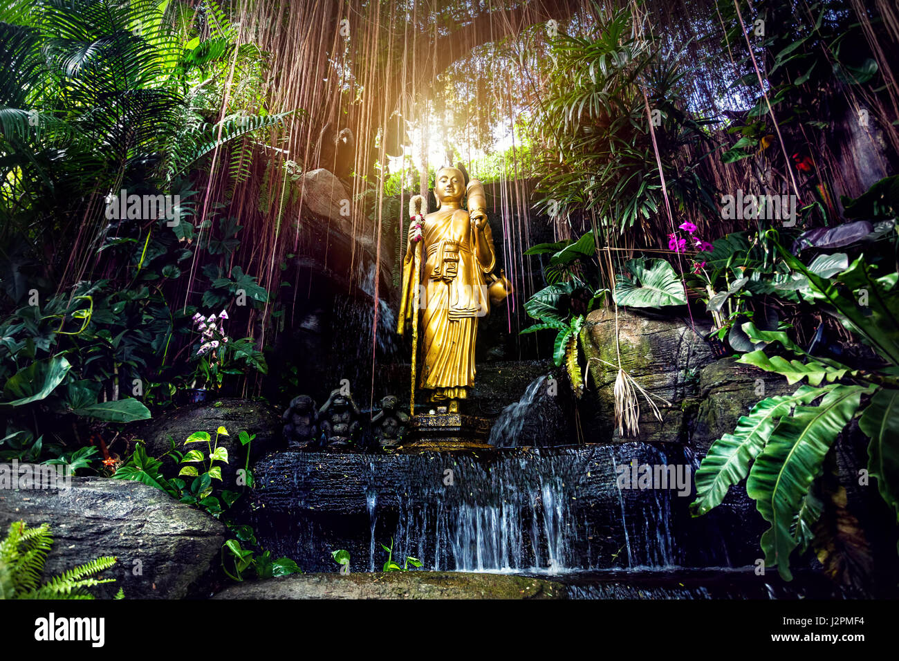 Estatua de Buda de oro en el jardín tropical con cascada en la Montaña Dorada, el templo Wat Saket en Bangkok Foto de stock