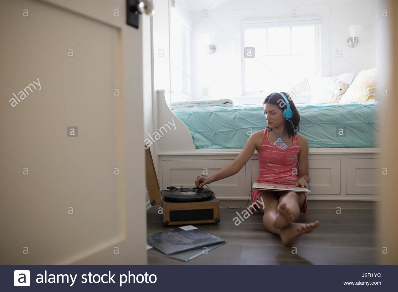 Adolescente escuchando música registros con tocadiscos y auriculares en dormitorio Foto de stock
