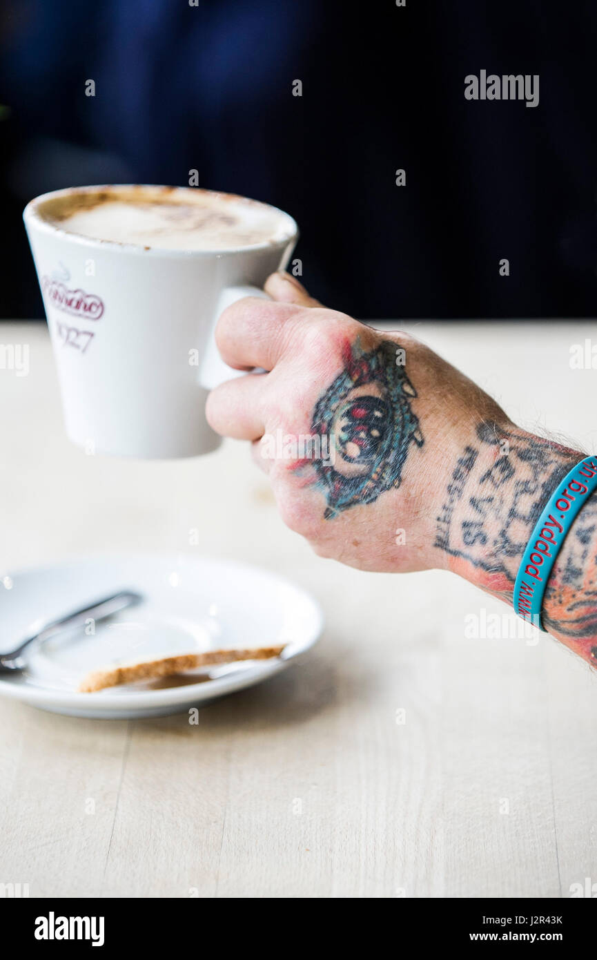 Una taza de café se celebró en una mano tatuada tatuajes diseños de descanso del café café Foto de stock