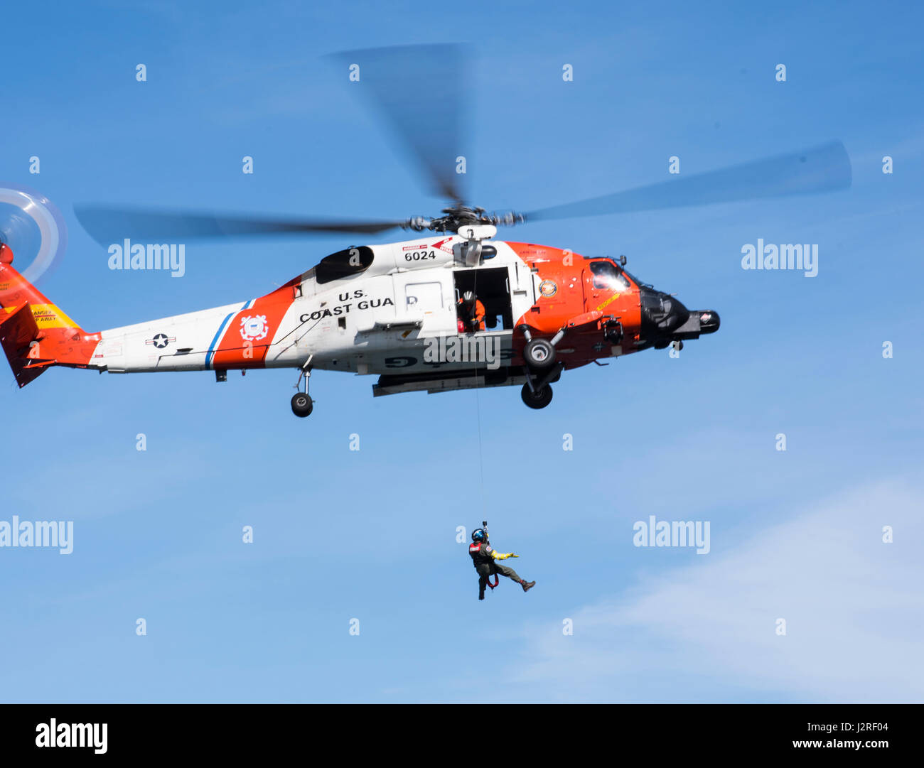 Un miembro de la tripulación de la Estación Aérea de San Diego está siendo alzada hasta una guardia costera MH60 Helicóptero Jayhawk en Point Vicente Lighthouse en Rancho Palos Verdes, California el 26 de abril de 2017. La formación contribuye consistentemente las tripulaciones estancia adepto de situaciones donde tendrán que realizar un acantilado de rescate. (Ee.Uu. Coast Guard foto por Suboficiales DaVonte 3ª clase' ósea) Foto de stock