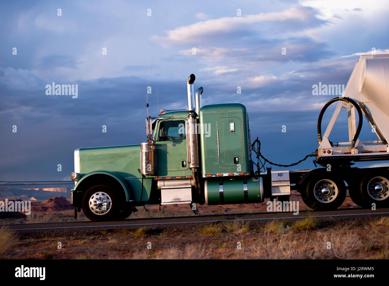Super classic green big rig semi-camión y remolque a granel y tall escape  tubos cromados en la carretera contra el azul cielo tormentoso Fotografía  de stock - Alamy