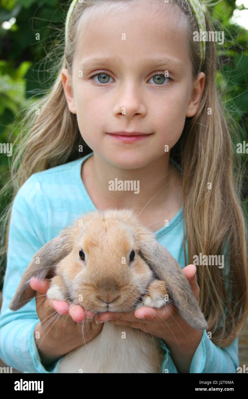 Una niña sostiene un conejo pequeño Foto de stock